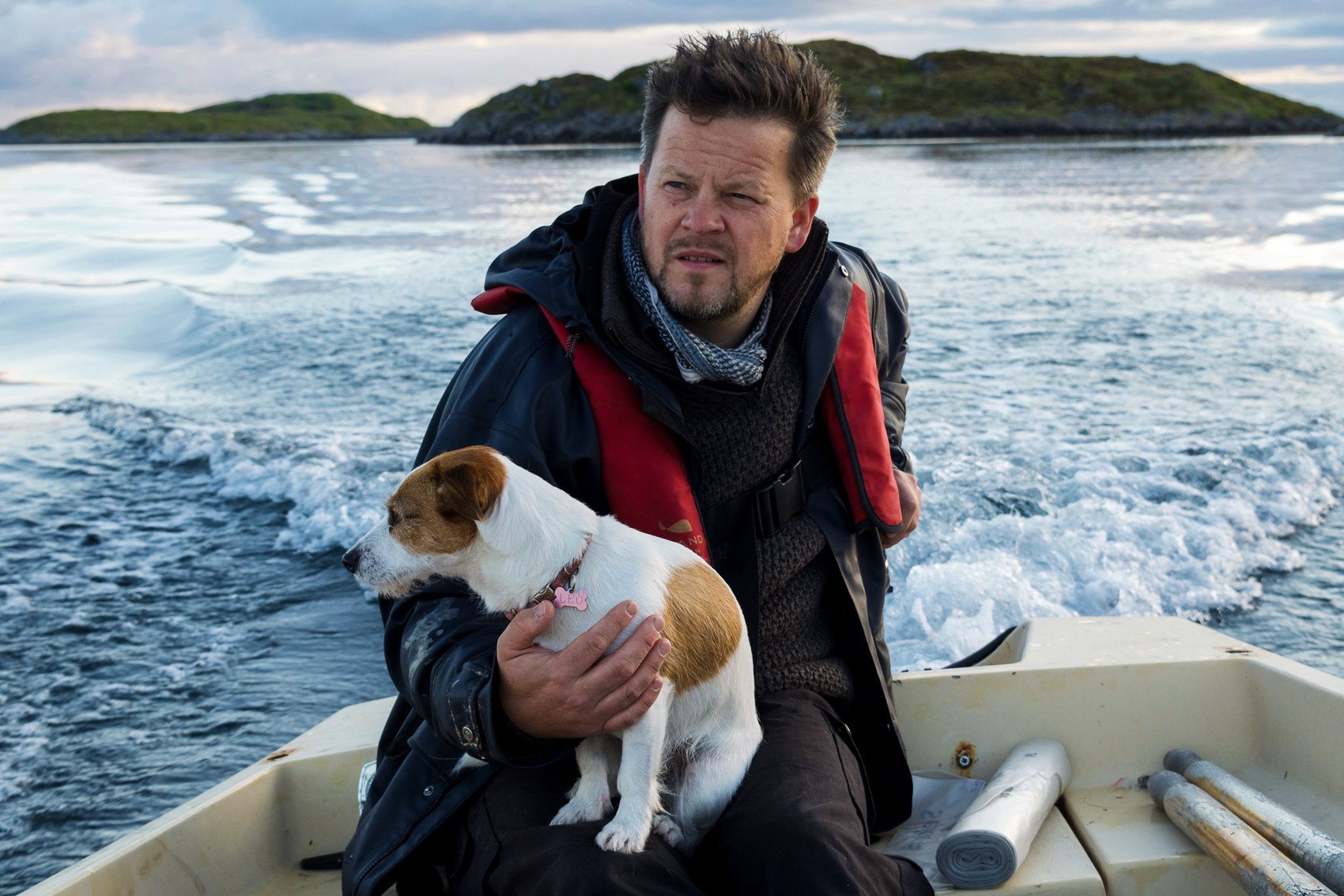 Håvard Lund and his dog Leo riding in a small boat off the coast of Fleinvær, Norway.