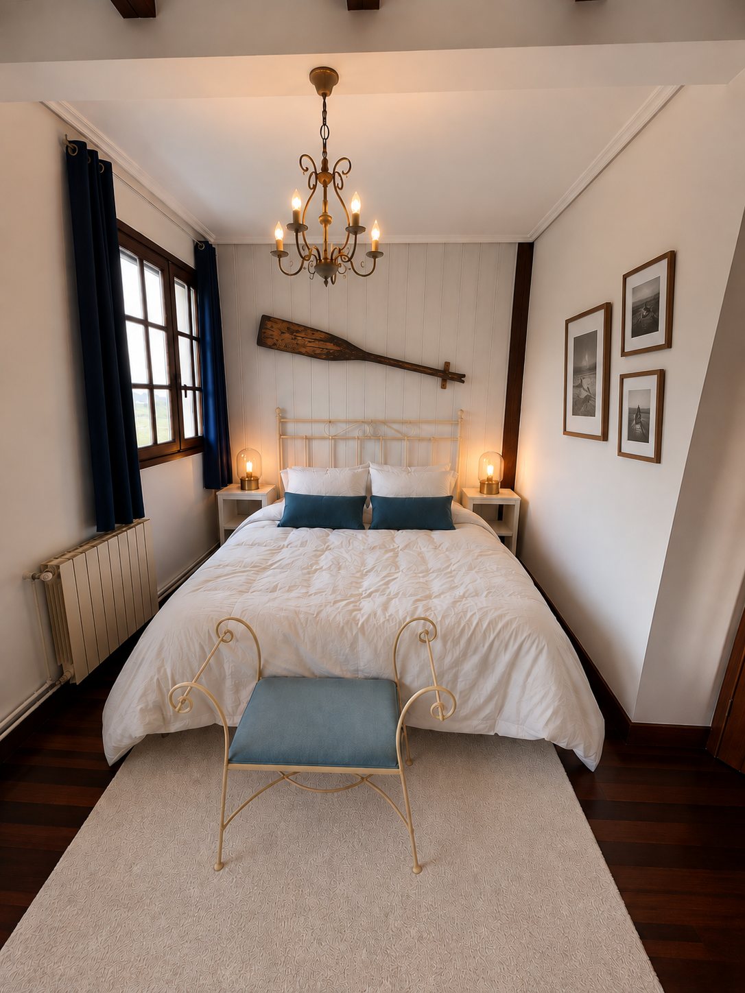 A bedroom with a ship's oar above the headboard and framed boat photographs on the wall.