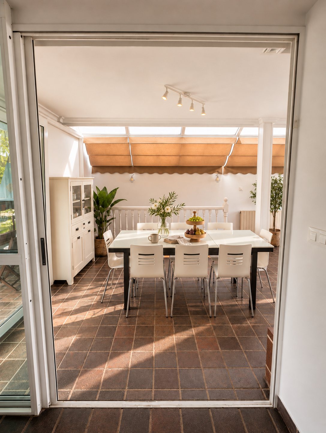 A covered terrace with a dining table, opening onto the house through glass doors.