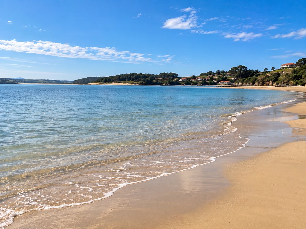 A woman wading into the clear turquoise water at Playa Usil, with the sandy beach and coastal hills beyond.