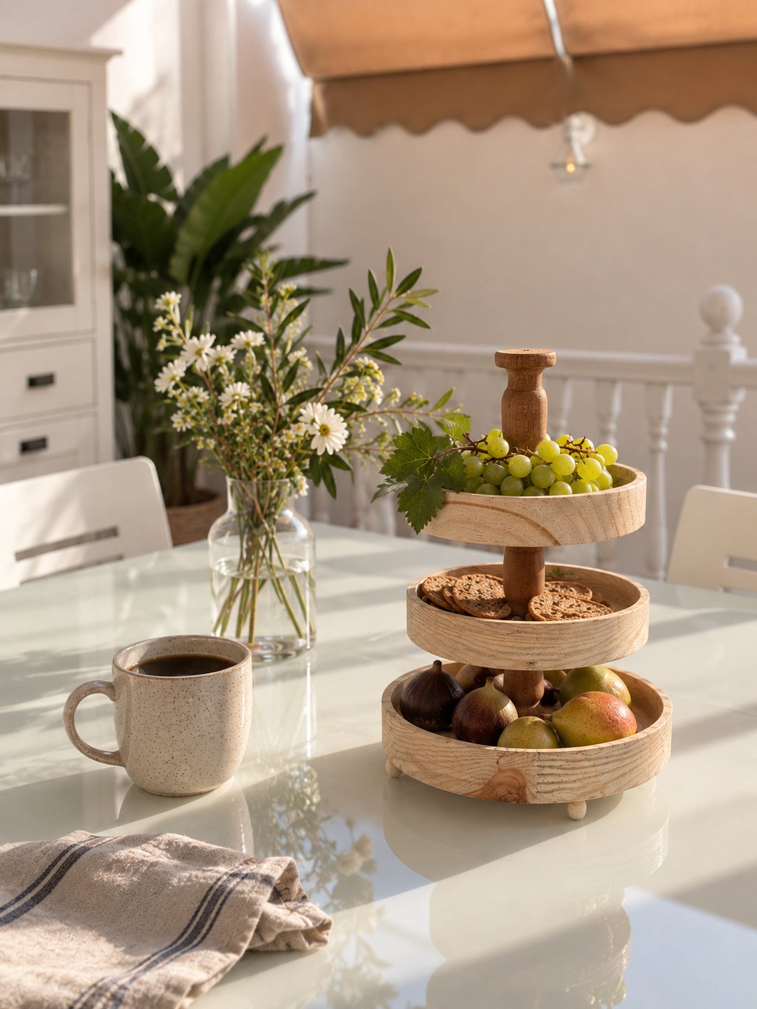 A styled table with a tiered stand of fruit, coffee and fresh flowers.