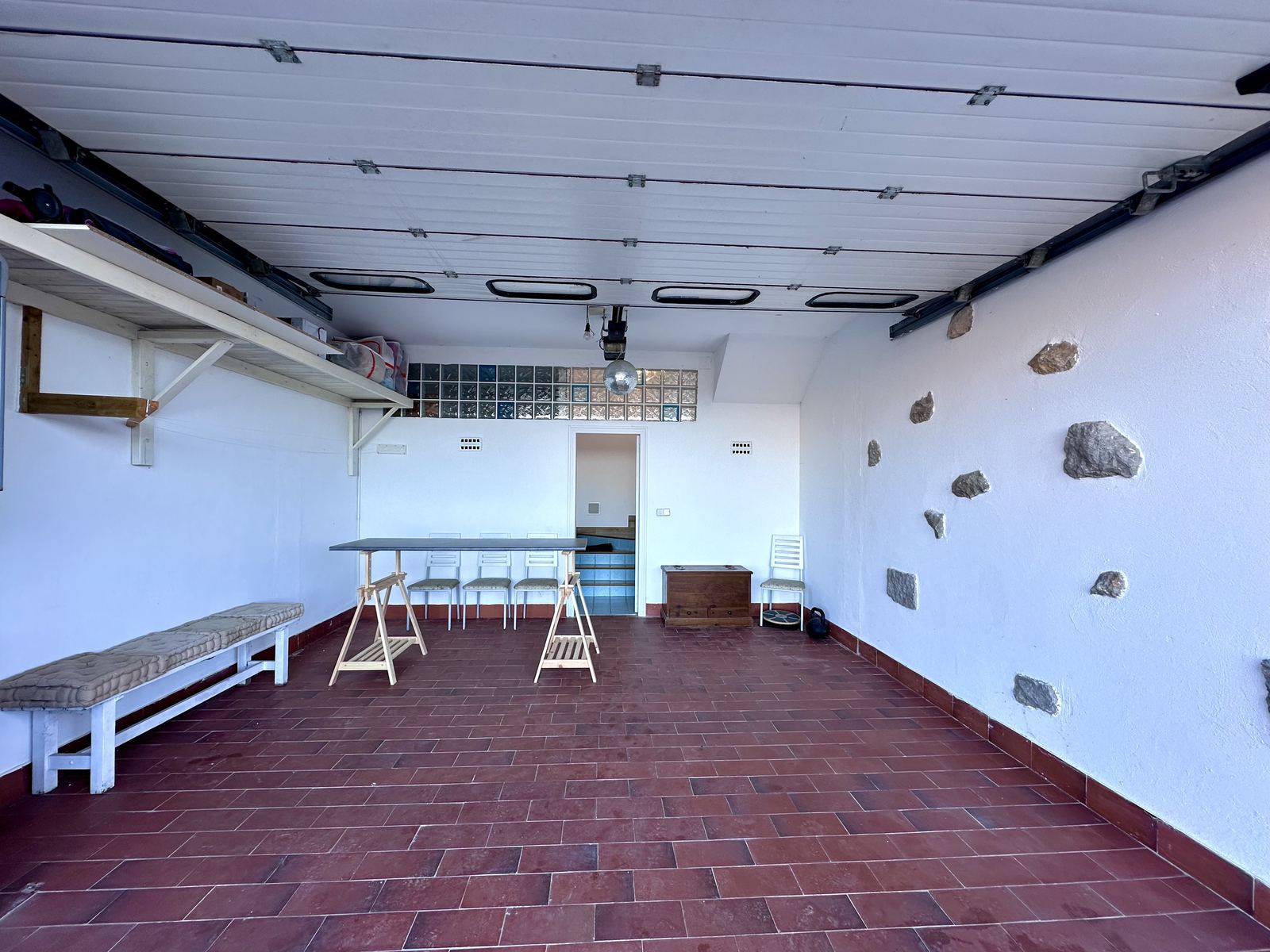 The garage studio, with long worktables and stools, ready for a residency.