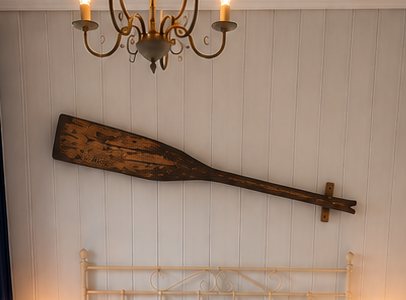 A hand-carved wooden oar mounted above a bedroom headboard.