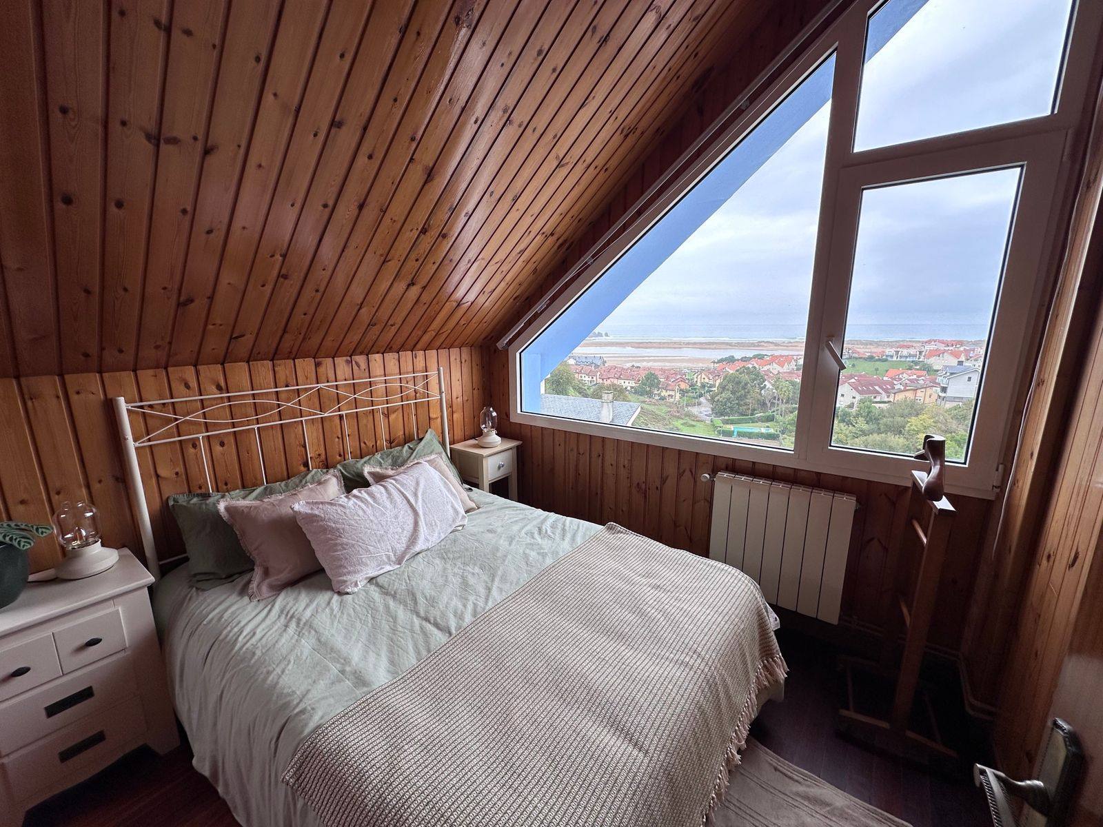 A pine-panelled attic bedroom with a large angled window looking over the estuary and the sea.