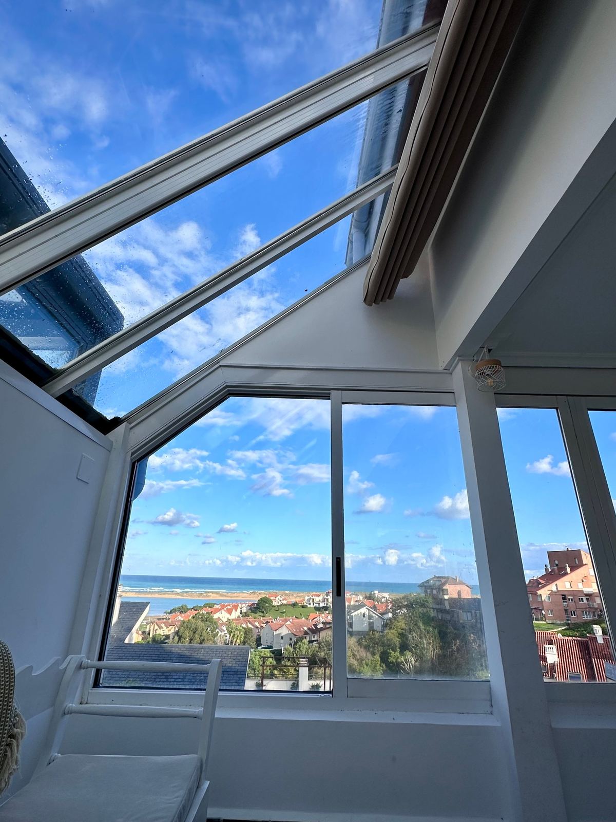 The sunroom's angled windows and skylight, framing the sea and village rooftops.