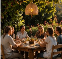 A group sharing dinner together at a long outdoor table under string lights.